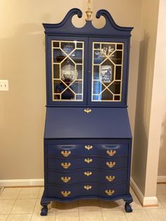 a blue dresser with two glass doors and gold trimmings on the top shelf