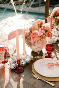 the table is set with pink flowers, candles and wine glasses for an elegant dinner