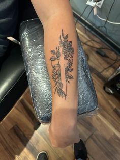 a woman's arm with a cross and flowers on it