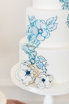 a three layer white cake with blue flowers on it