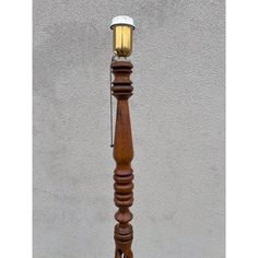 an old fashioned wooden floor lamp with a light on it's top and chain around the base