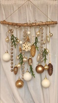 a bunch of ornaments hanging from a wooden stick on a curtain with white drapes