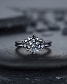 a white gold ring with an old - fashioned diamond center stone, set on top of a rock