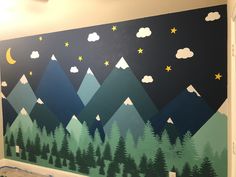 a wall painted with mountains and stars in the night sky, trees and clouds on it