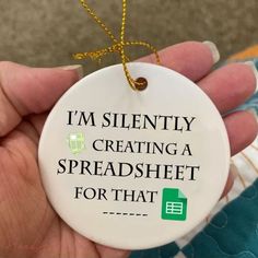 a hand holding a ceramic ornament that says i'm silently creating a spreadsheet for that