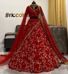 a red bridal gown on display in front of a couch