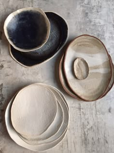 several bowls and plates are arranged on a table top, including one with a stone in the middle