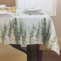 a table with a white and green forest print on it is set for two people