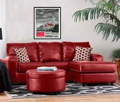 a red couch and ottoman in a living room with a colorful painting on the wall