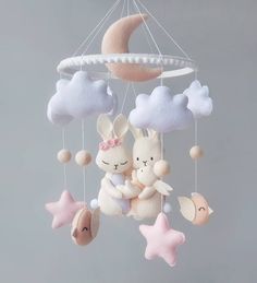 a mobile with two stuffed animals hanging from it's sides in the shape of a moon and clouds