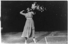 an old black and white photo of a woman playing tennis