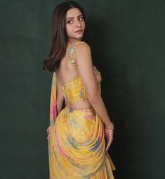 a woman in a yellow sari is posing for the camera with her hands on her hips