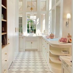 a white kitchen with checkered flooring and cabinets in the corner, next to a window