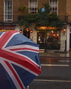 an open umbrella with the british flag on it in front of a building and street