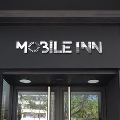 the entrance to mobile inn with large glass doors and metal letters on it's side