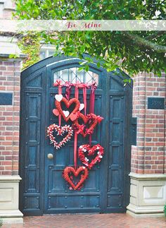 a couple of heart shaped wreaths are hanging on the door to a brick building