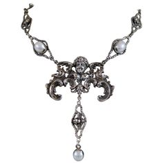 This one of a kind sterling silver drop necklace accentuates heavenly elements found throughout history in sacred adornments, sculpture and architecture. A grand figural angel establishes the bold center element for this necklace which has a winged cherub link lavalier drop with a 12 x 10 mm oval freshwater pearl. Jill's original cherubic links with filigree form unique chaining with intermittent 12 x 10 mm Freshwater pearl cabochons. We hope you will review our numerous pictures from every angle so you can see the fine detail and beauty of this wonderful original drop necklace. If you need additional pictures please let us know as we are always happy to provide them. • A finely-wrought sterling silver lavalier drop necklace • 19.5 in. figural cherub link chain • Five 12 x 10 mm freshwater Baroque Angel, Silver Drop Necklace, Gold Lariat Necklace, Modern Necklaces, Freshwater Pearl Necklaces, Multi Strand Necklace, Lariat Necklace, Drop Necklace, Baroque Pearls