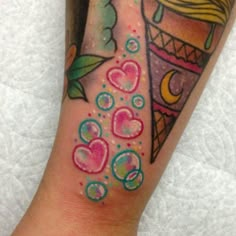 a colorful tattoo on the arm of a girl with hearts and an ice cream cone