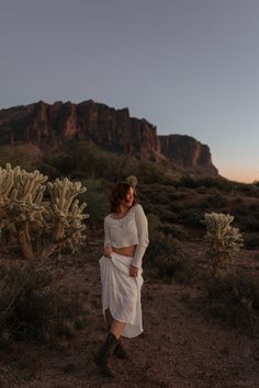 a woman standing in the desert at sunset