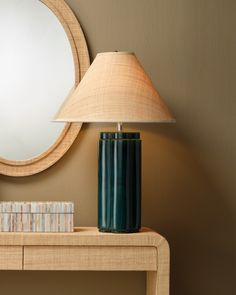 a table with a lamp, mirror and books on it