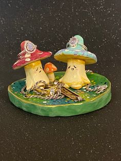 two small ceramic mushrooms sitting on top of a green platter with chains and charms