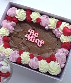 a cake in a box with the word be mine on it and red, white, and pink frosting