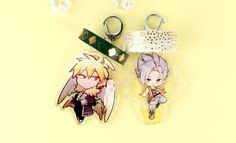 two keychains with anime characters on them sitting next to each other, one has an angel and the other is a demon