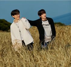 two young men standing next to each other in a field