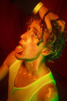 a man with curly hair wearing a yellow tank top