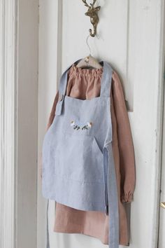 a blue apron hanging on the wall next to a white door with an iron hook