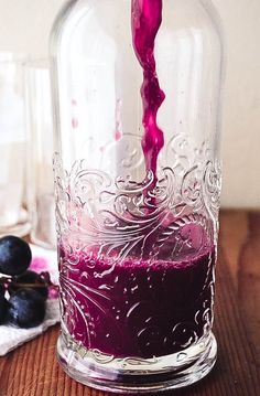 a glass jar filled with purple liquid next to blueberries