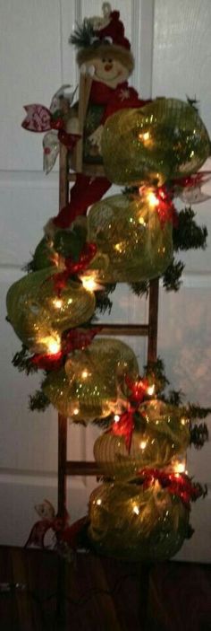 a christmas tree is decorated with lights and bows on it's bottom tier, in front of a door