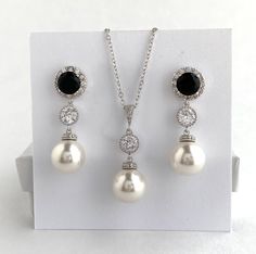 I've created this elegant black cubic zirconia and pearl bridal  jewelry set in rhodium plated brass setting and the set includes: # Earrings feature large 12mm Austrian crystal pearls that dangle from brilliant cut black cubic zirconia with halo setting 12mm ear stud and round     cubic zirconia connector. Halo setting gives a brilliantly beautiful effect. Total length of the earrings is 3.8 cm.  #Classic pearl bridal necklace and pendant set with rhodium plated and bail and round cubic zirconi Formal Black Round Jewelry Sets, Elegant Black Jewelry Set For Wedding, Black Round Pearl Drop Jewelry, Black Crystal Jewelry Sets For Wedding, Black Pearl Drop Round Jewelry, Black Pearl Drop Jewelry For Anniversary, Black Crystal Jewelry For Anniversary, Black Sterling Silver Jewelry With Pearl Drop, Formal Black Jewelry With Pearl Pendant