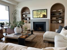 a living room filled with furniture and a fire place in front of a large window