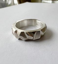 A random facet ring, all hand carved, shows different angles, ragged peaks and flat plains as one turns it.  Each twist and turn provides a different landscape to the wearer.  Even with peaked corners, there is nothing sharp to the touch.  Each angle is carefully filed and sanded and the finish is a soft, flat matte.  This ring has a nice heft to it as it was required to carve the depth of some of the facets.  I have also sold this band in 14K white gold as a wedding band however, it also makes for a great everyday ring. IN STOCK Size:  10 Wax Ring, Faceted Ring, Carved Ring, Wax Carving, Handmade Sterling Silver Rings, Art Jewelry Contemporary, Everyday Ring, Contemporary Ring, Jewelry Accessories Ideas