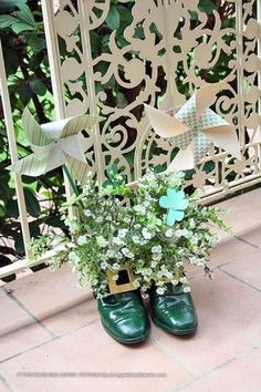 a pair of green shoes sitting on top of a brick floor next to a planter