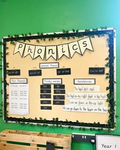 a bulletin board with writing on it in front of a green wall and wooden bench