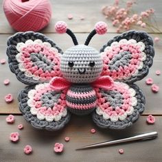 a crocheted butterfly sitting on top of a wooden table next to yarn and scissors