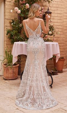 a woman in a wedding dress standing next to a table with pink flowers on it