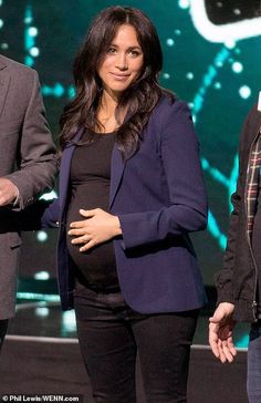 a pregnant woman standing next to a man on stage