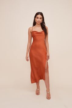 a woman is wearing an orange dress with one leg slited and the other side split open