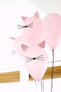 three pink balloons with cat heads on them