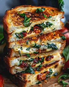 four slices of grilled cheese stacked on top of each other with tomatoes and basil