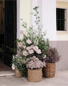 three baskets filled with flowers sitting on the side of a building next to a door