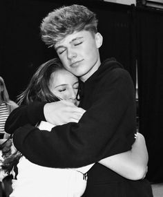 two people hugging each other while standing in front of a stage with one person holding the other