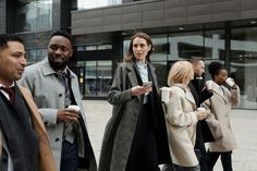 a group of people standing around each other in the street talking and drinking coffee together