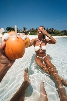 a woman sitting in the water holding an orange