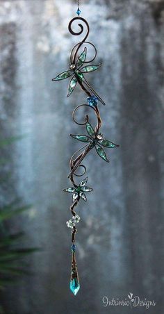 a wind chime hanging from the side of a tree with blue and green crystals