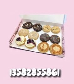 a box filled with lots of different types of donuts on top of a pink background