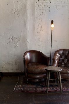 two brown leather chairs sitting next to each other on top of a carpeted floor